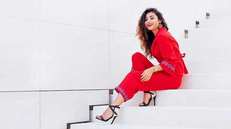 Fashion subject in a red outfit on white steps.